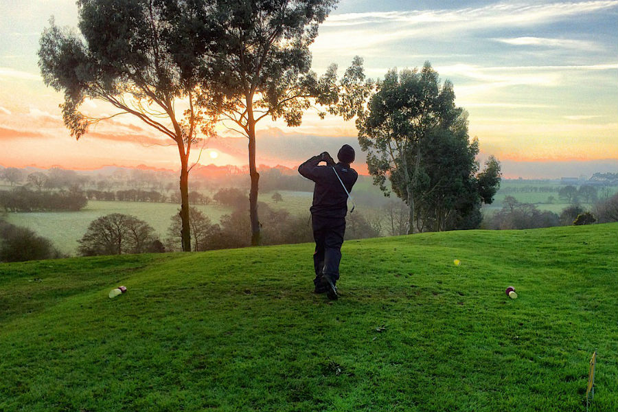 golfer teeing off at sunrise